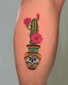 a tattoo on the leg of a person with a potted plant and flowers painted on it