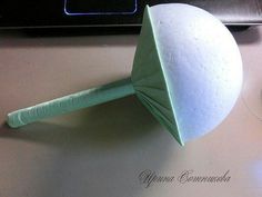 an origami ball on top of a paper cone with a green handle sitting next to a computer keyboard