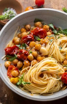 pasta with chickpeas and tomatoes in a white bowl on a wooden table top