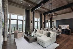 a living room filled with lots of furniture next to large windows on top of a wooden floor