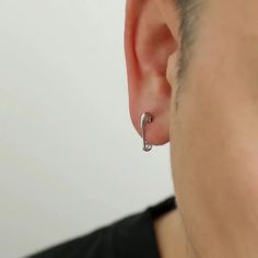 a man wearing a pair of silver hoop earrings in front of his face and back of the ear