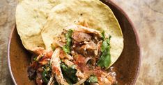 a bowl filled with tortilla shells and shredded meat on top of it's sides