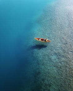 an aerial view of a boat floating in the blue water with clear skies above it