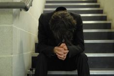 a man sitting on the stairs with his head in his hands