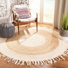 a round rug with tassels on it in front of a chair and window