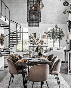 a dining room table and chairs in front of a spiral stair case with plants on it