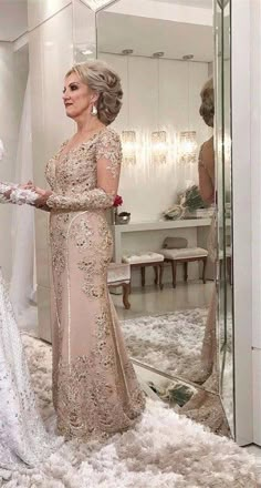 a woman in a wedding dress looking at herself in the mirror with another woman standing next to her