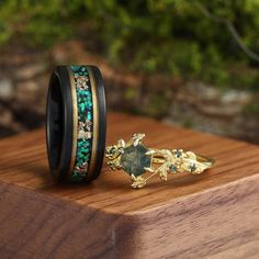 a couple of rings sitting on top of a wooden table next to some rocks and plants