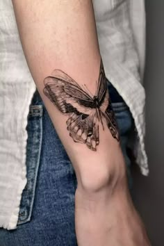 a woman's arm with a butterfly tattoo on the left side of her arm