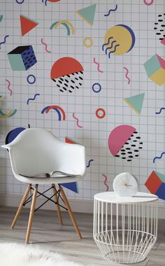 a white chair sitting in front of a wall with colorful geometric designs on the walls