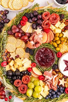 a platter filled with cheese, crackers, grapes, and other food items