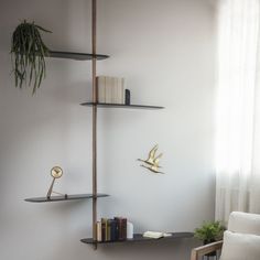 a shelf with books and plants on it next to a chair in front of a window