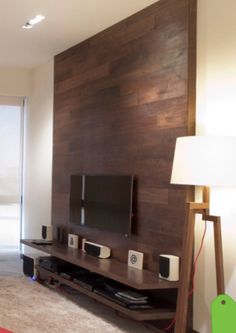 a flat screen tv sitting on top of a wooden shelf in a living room next to a lamp