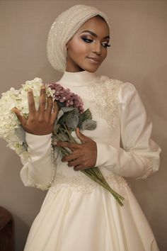 a woman in a white dress holding flowers and wearing a turban on her head