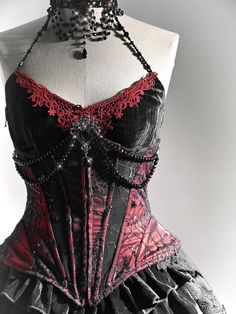 Stunning Victorian Goth Corset: This exquisite piece features a handmade black bead chain neckline adorned with a removable brooch. The corset is reinforced with four metal bones for a perfect fit and is crafted from a red, shiny fabric overlaid with intricate spiderweb lace. Embrace your inner royalty with its regal vampire vibes.   	 		 			Size 			S 			M 			L 		 		 			Waist 			64 			68 			72 		 		 			Full Length 			31 			32 			33 		 		 			Upper Circumference 			88 			92 			96 		 		 			Hem Circ Dnd Clothes, Spiderweb Lace, Modern Mythology, Velvet Corset Top, Red Vampire, Gothic Spider, Vampire Fashion, Victorian Vampire, Vampire Clothes