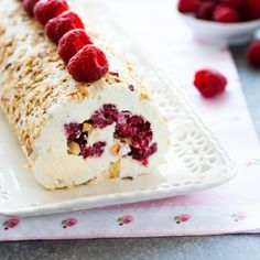 a white plate topped with a roll covered in raspberries