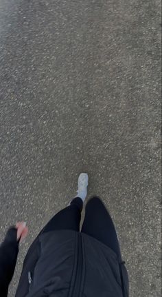 a person with their feet in the air and wearing black pants, standing on asphalt