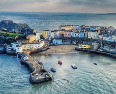 an aerial view of a small town by the water with boats in it and buildings on the shore