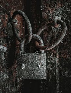 an old padlock with two rusty chains hanging from it's sides on a rusted wall