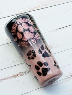 a pink and black cup with paw prints on the side sitting on a white wooden surface