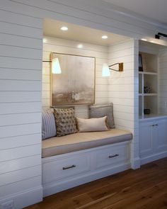 a room with white walls and wood flooring has a window seat on the far wall