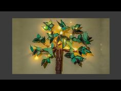 a lighted tree made out of paper with leaves on it's branches and lights in the shape of butterflies