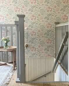 an open door leading to a room with floral wallpaper on the walls and wooden floors