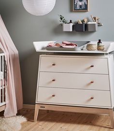 a baby's room with a dresser, crib and pictures on the wall