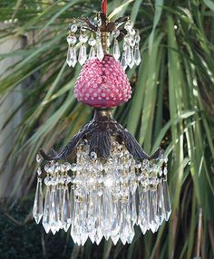 a pink chandelier hanging from a palm tree