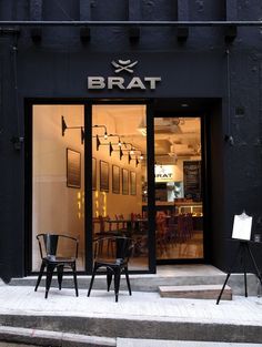 two black chairs sitting in front of a storefront with the word brat on it