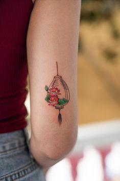 a woman with a tattoo on her arm holding a red flower in the other hand