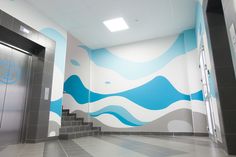 an elevator with blue and white waves painted on the wall next to it's doors