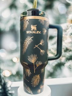 a travel mug with the name stanley on it sitting next to a christmas ornament