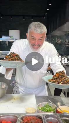 a man holding two plates with food on it in front of other bowls and pans