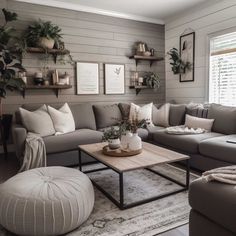 a living room with gray couches and white pillows on the walls, potted plants