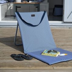 a blue and white striped bag sitting on top of a wooden floor next to sandals