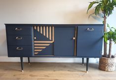 a blue and gold sideboard with three drawers on one end, two plants in the other