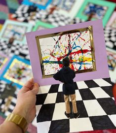 a person holding up a piece of paper with a painting on it