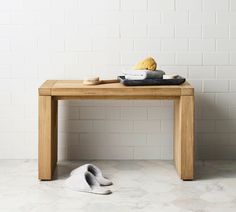 a wooden table with a pair of slippers on it next to a white brick wall