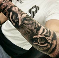 a man's arm with a tiger tattoo on it and an eyeball in the middle