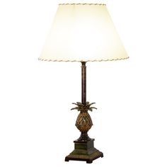 a table lamp with a white shade on it's base and a gold pineapple design