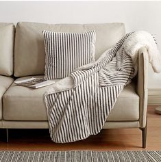 a couch with a blanket on top of it next to a lamp and rugs