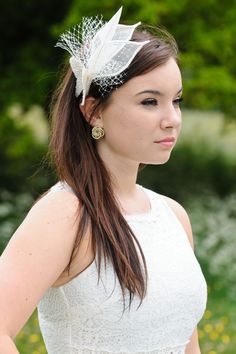 a woman with long hair wearing a white dress and a feathered headpiece in her hair