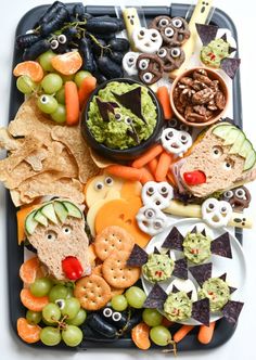 a tray filled with crackers, vegetables and other snacks to be eaten for halloween