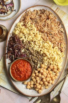 a plate full of pasta, beans and sauces on a table with utensils