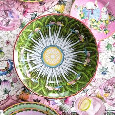 a table topped with lots of plates covered in green and pink flowers on top of it