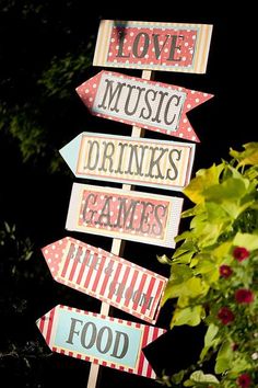 a sign that has some signs on it in front of trees and bushes with flowers