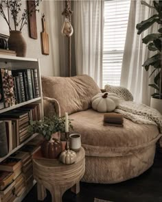 a living room with a round couch and bookshelf in the corner next to a window