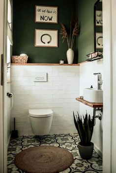 a white toilet sitting in a bathroom next to a green painted wall and potted plant