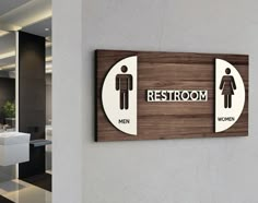 a restroom sign on the wall next to a sink and toilet in a modern bathroom